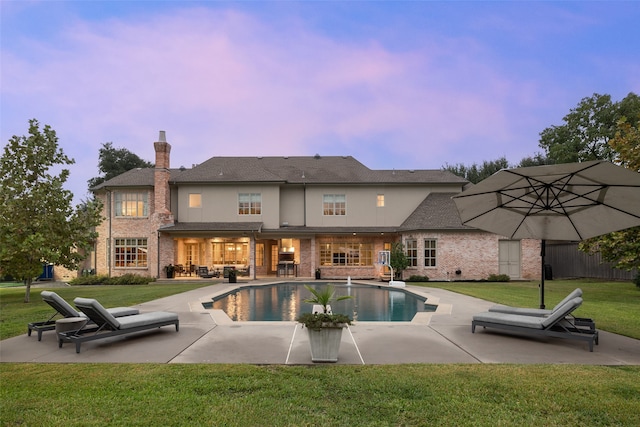 pool at dusk featuring a yard