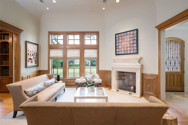 living room with built in shelves, high vaulted ceiling, and light hardwood / wood-style flooring