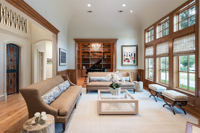 living room featuring a notable chandelier, light wood-type flooring, and high vaulted ceiling