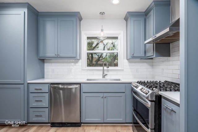 kitchen featuring sink, wall chimney exhaust hood, backsplash, appliances with stainless steel finishes, and light wood-type flooring