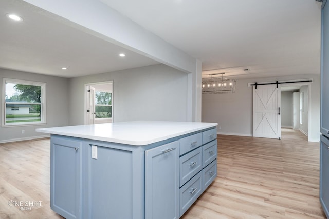 kitchen featuring a barn door, a center island, light hardwood / wood-style flooring, and hanging light fixtures