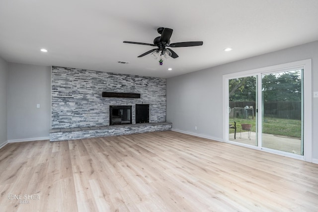 unfurnished living room featuring ceiling fan, light hardwood / wood-style floors, and a stone fireplace