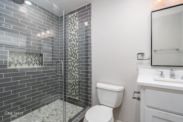 bathroom featuring a shower with door, vanity, a textured ceiling, and toilet