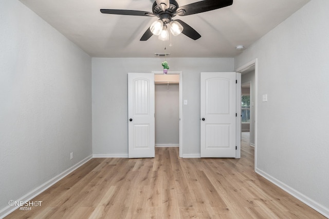 unfurnished bedroom with a walk in closet, light wood-type flooring, a closet, and ceiling fan