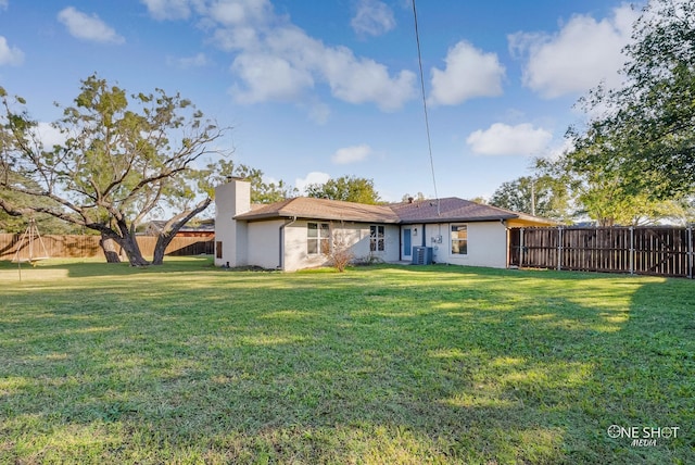 rear view of property featuring central AC unit and a yard