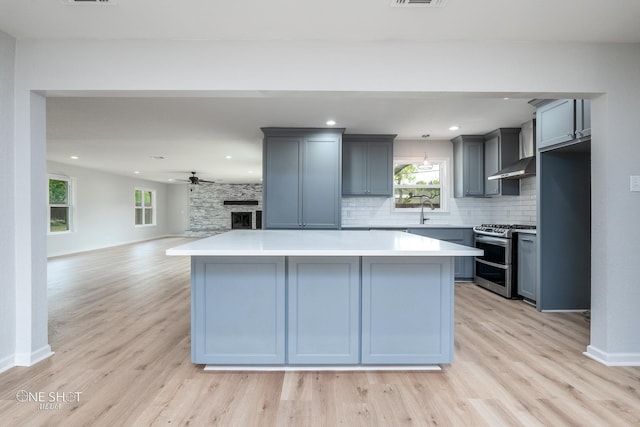 kitchen featuring light hardwood / wood-style flooring, stainless steel range with gas cooktop, ceiling fan, and gray cabinetry