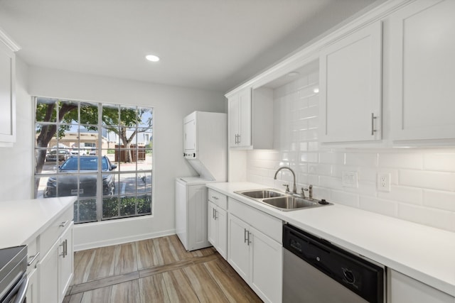 kitchen featuring decorative backsplash, stacked washing maching and dryer, stainless steel dishwasher, sink, and white cabinetry