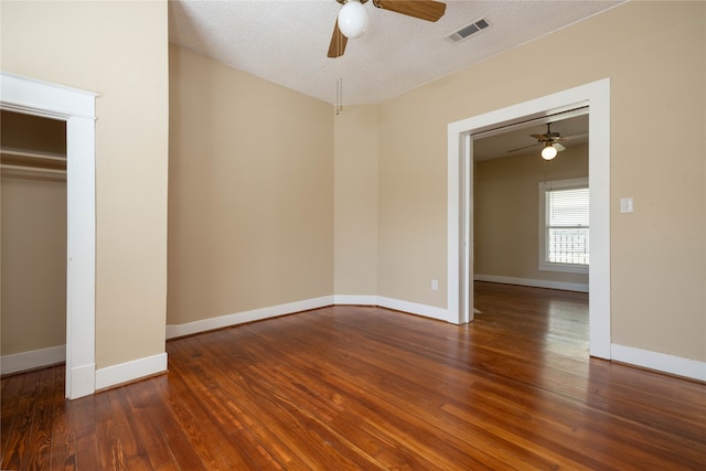 unfurnished bedroom featuring a textured ceiling, ceiling fan, dark wood-type flooring, and a closet