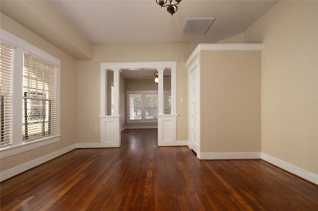 spare room featuring dark hardwood / wood-style floors, ceiling fan, ornate columns, and a textured ceiling