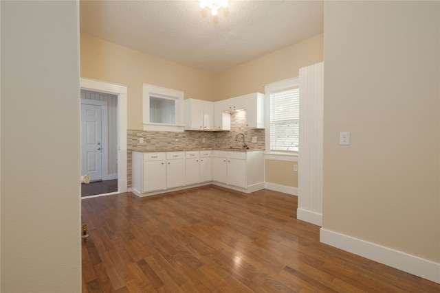 kitchen featuring decorative backsplash, a textured ceiling, sink, white cabinets, and dark hardwood / wood-style floors