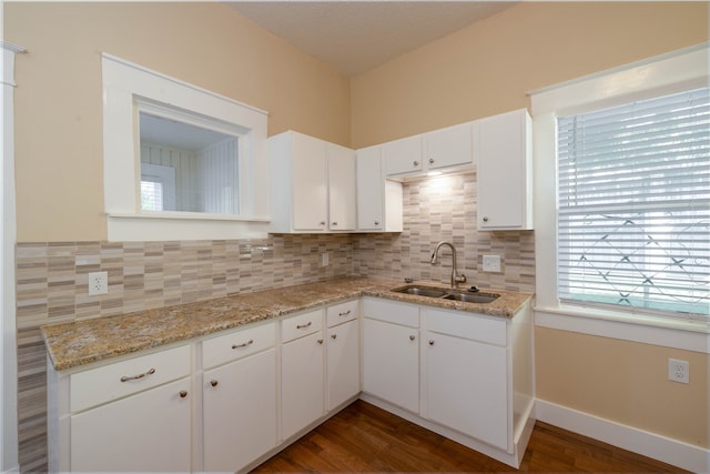 kitchen featuring dark hardwood / wood-style floors, light stone countertops, white cabinetry, and sink