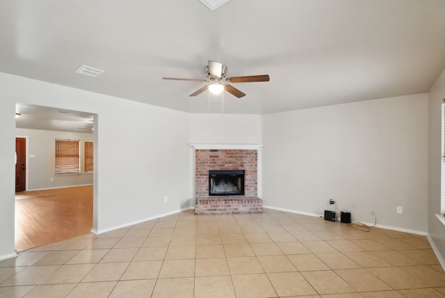 unfurnished living room featuring ceiling fan, light tile patterned floors, and a fireplace