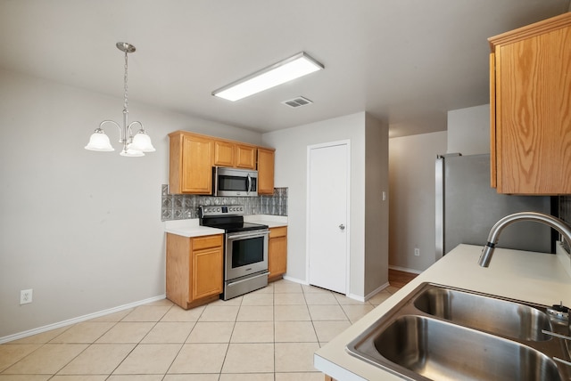 kitchen with sink, tasteful backsplash, light tile patterned floors, pendant lighting, and stainless steel appliances