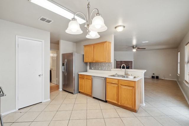 kitchen with sink, hanging light fixtures, light tile patterned floors, ceiling fan with notable chandelier, and appliances with stainless steel finishes