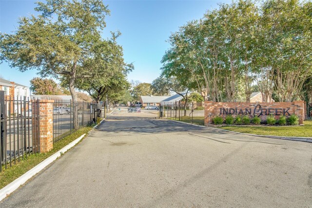 view of street with a gate, a gated entry, and curbs