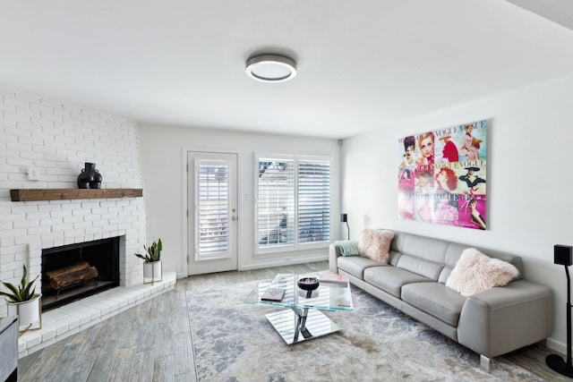 living room with a brick fireplace and hardwood / wood-style flooring