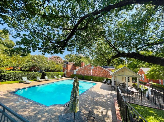 community pool featuring fence, an outdoor structure, an exterior structure, and a patio