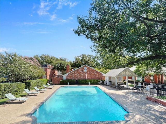 view of swimming pool with an outbuilding, a patio, fence, and a fenced in pool