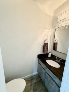 half bath featuring toilet, baseboards, and vanity