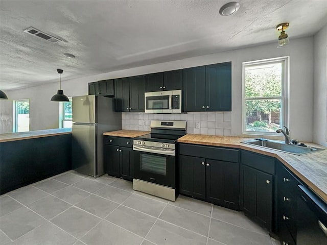 kitchen featuring tasteful backsplash, visible vents, butcher block counters, appliances with stainless steel finishes, and a sink