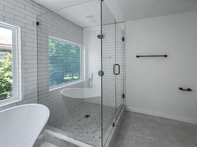 bathroom featuring a stall shower, a freestanding bath, and baseboards