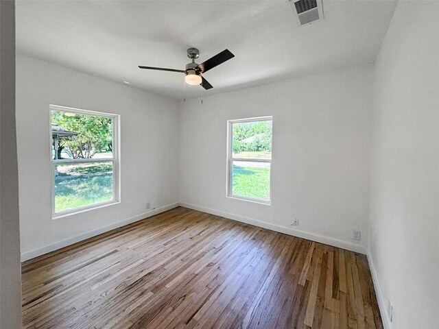 empty room featuring visible vents, baseboards, hardwood / wood-style floors, and a ceiling fan