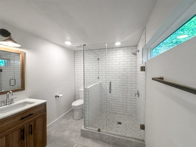 bathroom with vanity, a shower stall, toilet, and baseboards