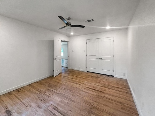 unfurnished bedroom with a ceiling fan, wood finished floors, visible vents, baseboards, and a closet