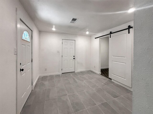 below grade area with visible vents, baseboards, and a barn door