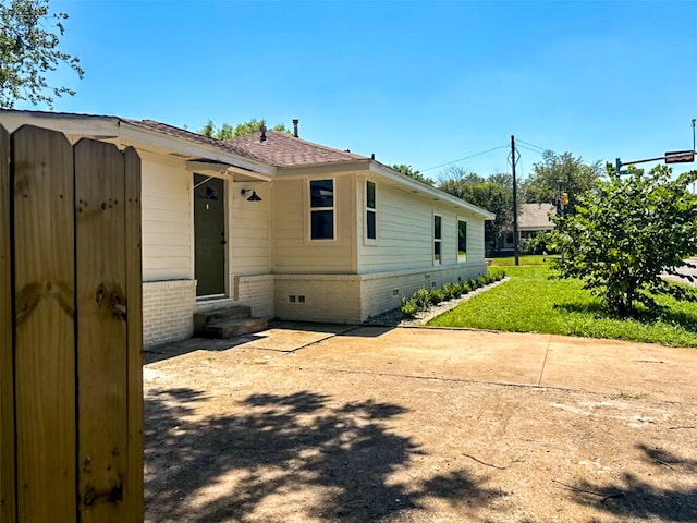 view of home's exterior with a lawn, entry steps, a shingled roof, crawl space, and brick siding