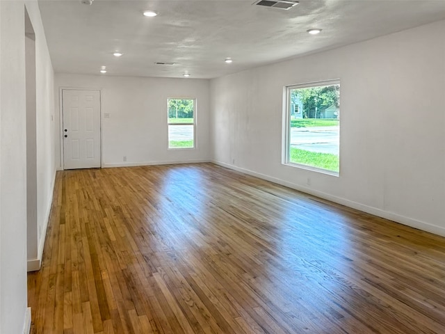 empty room with visible vents, baseboards, and hardwood / wood-style flooring