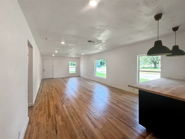 unfurnished living room featuring visible vents, baseboards, a healthy amount of sunlight, and light wood-style flooring