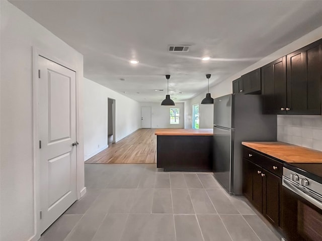 kitchen with visible vents, freestanding refrigerator, electric range oven, open floor plan, and backsplash