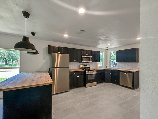 kitchen featuring stainless steel appliances, decorative backsplash, visible vents, and butcher block counters