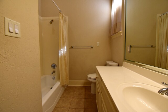 full bathroom with tile patterned floors, shower / tub combo with curtain, vanity, and toilet