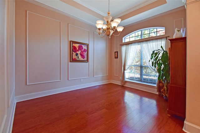 unfurnished room with a notable chandelier, crown molding, dark wood-type flooring, and a tray ceiling