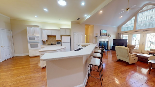 kitchen with a kitchen island, a healthy amount of sunlight, white appliances, and light wood-type flooring