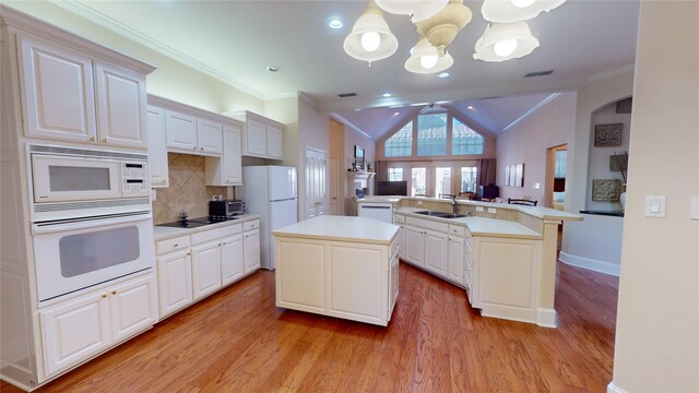 kitchen with pendant lighting, white appliances, a kitchen island, and crown molding