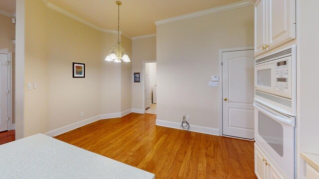 dining space featuring light hardwood / wood-style flooring, crown molding, and a notable chandelier