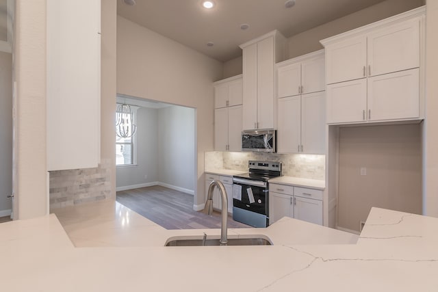 kitchen featuring appliances with stainless steel finishes, backsplash, light wood-type flooring, sink, and white cabinets