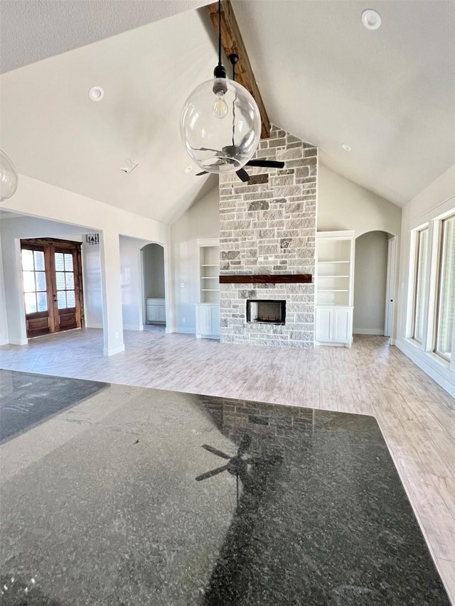 unfurnished living room with vaulted ceiling, ceiling fan, a fireplace, a textured ceiling, and built in features