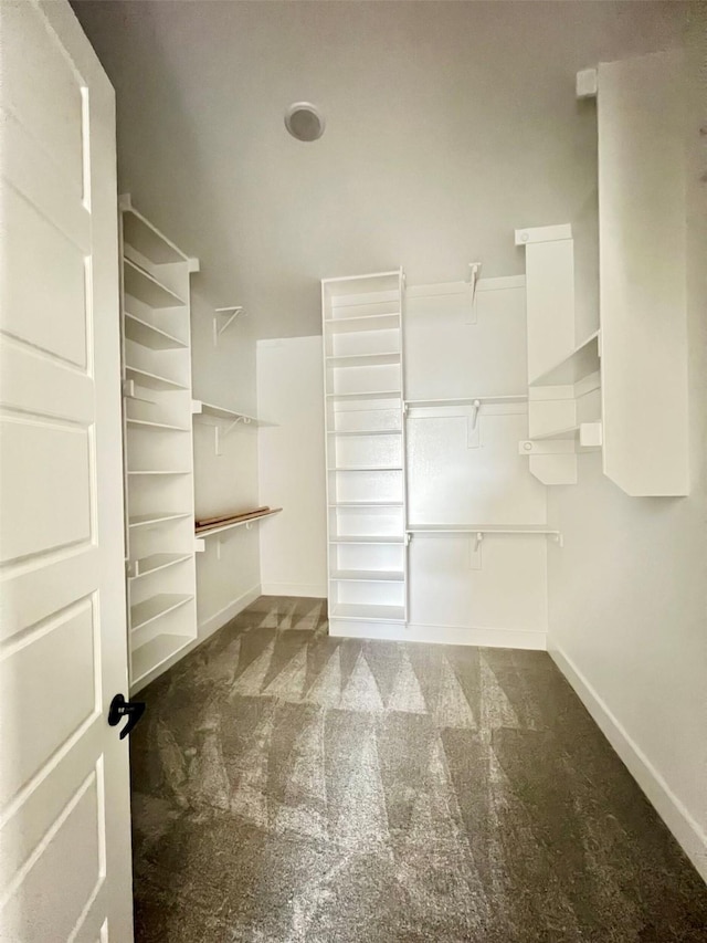 walk in closet featuring dark carpet