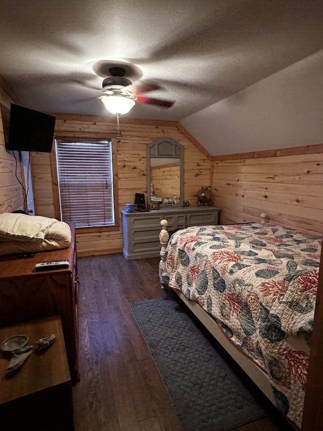 bedroom with ceiling fan, wood walls, dark wood-type flooring, and vaulted ceiling