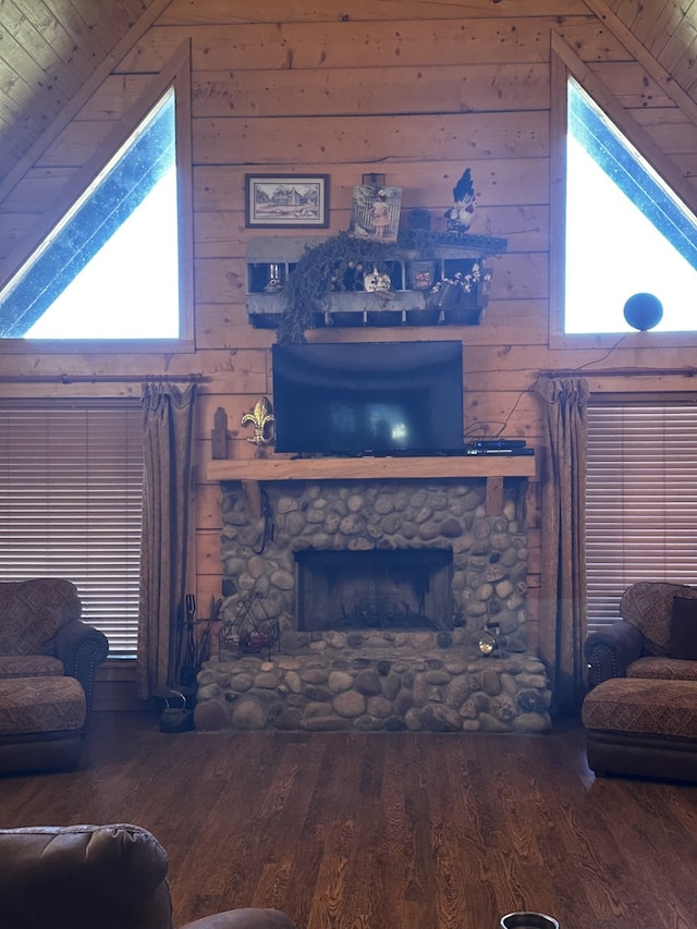 living room featuring plenty of natural light, a stone fireplace, and wood ceiling