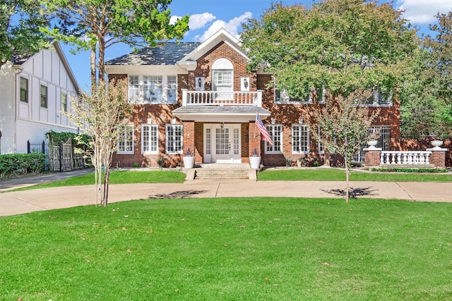 view of front of home featuring a front lawn, a balcony, and french doors