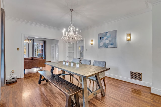 dining space featuring light hardwood / wood-style floors, ornamental molding, and french doors