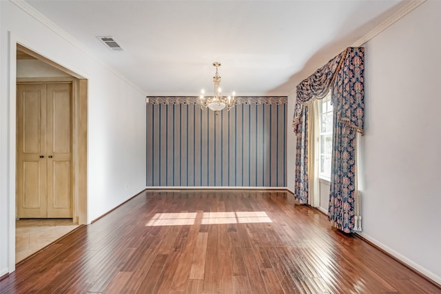 spare room featuring a chandelier, wood-type flooring, and crown molding