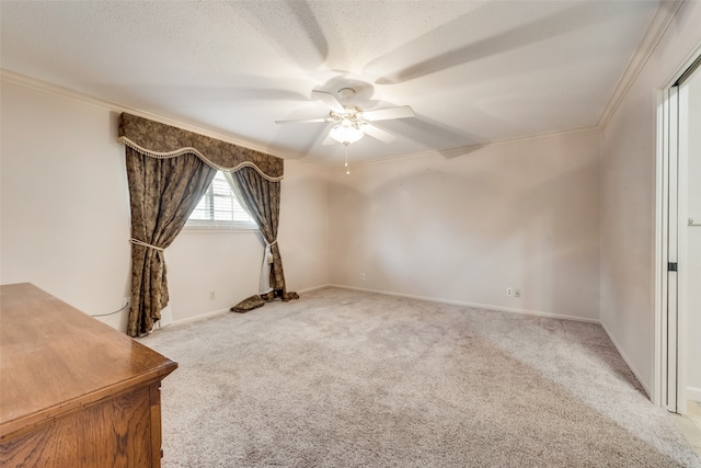 spare room with ceiling fan, light colored carpet, ornamental molding, and a textured ceiling