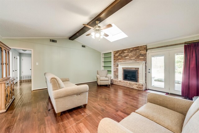 living room with a brick fireplace, dark hardwood / wood-style floors, lofted ceiling with skylight, and ceiling fan