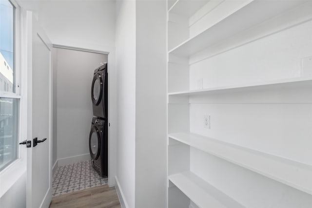 laundry room with light hardwood / wood-style flooring and stacked washer / drying machine